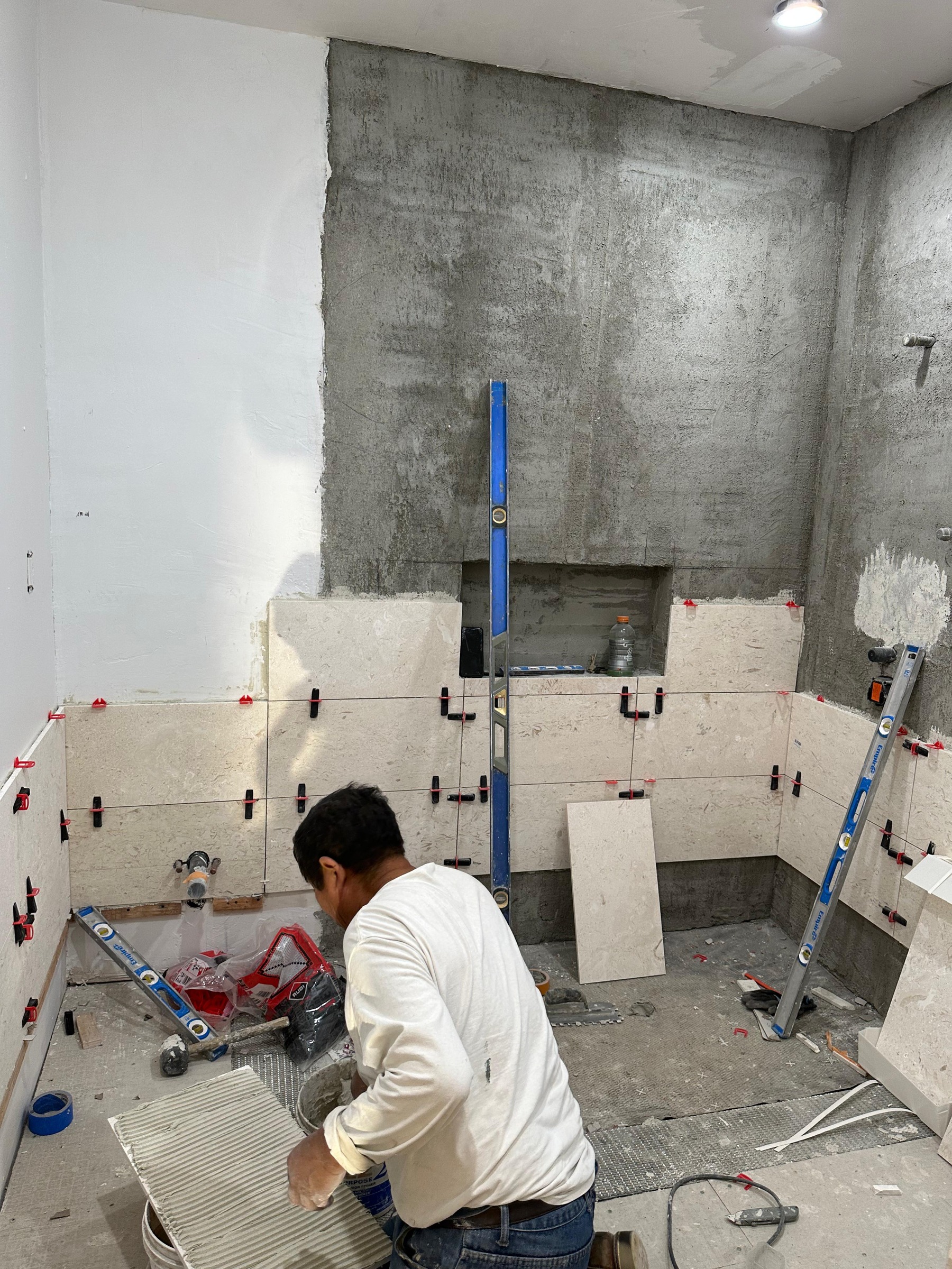 Emner Mendoza on his knees applying mortar, mid-tile install.