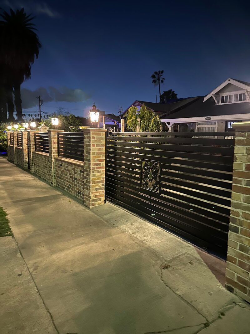 Iron gate at night with palm trees behind, soft streetlight.