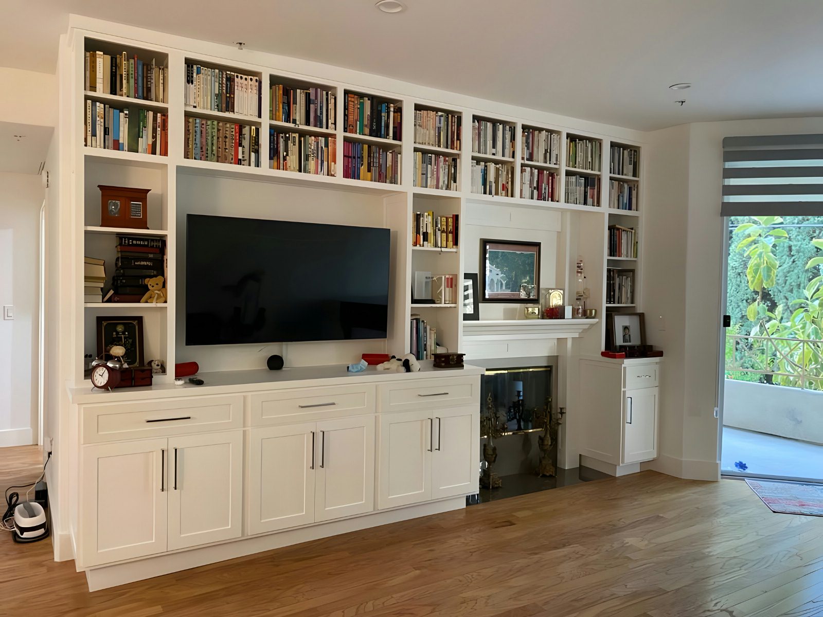 Floor-to-ceiling library wall built-in with shelved books and family photos, settled into by the homeowners.