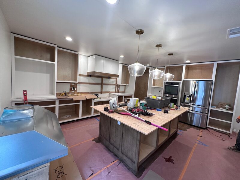 Empty kitchen with ductwork laid out on the floor before framing.