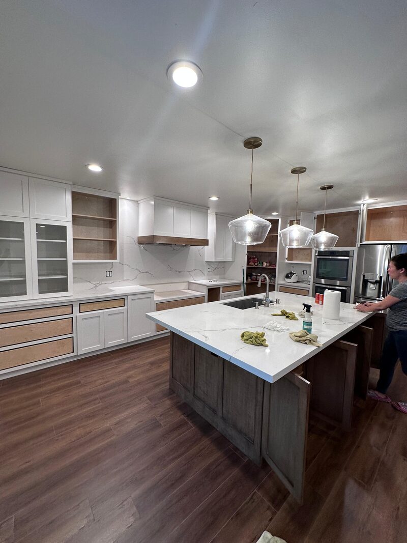 Newly-installed kitchen counter being wiped down with a spray bottle, mid-cleanup before final handoff.