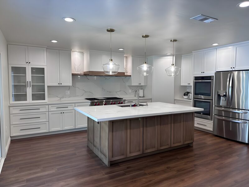 Finished kitchen: gray-wood island, calacatta backsplash, red-knob range, double oven, the room as a whole.