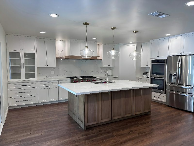 Finished kitchen: gray-wood island, calacatta backsplash, red-knob range, double oven, the room as a whole.